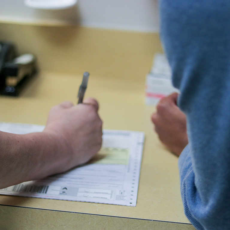 Close up of a student health staff member filling out a form.